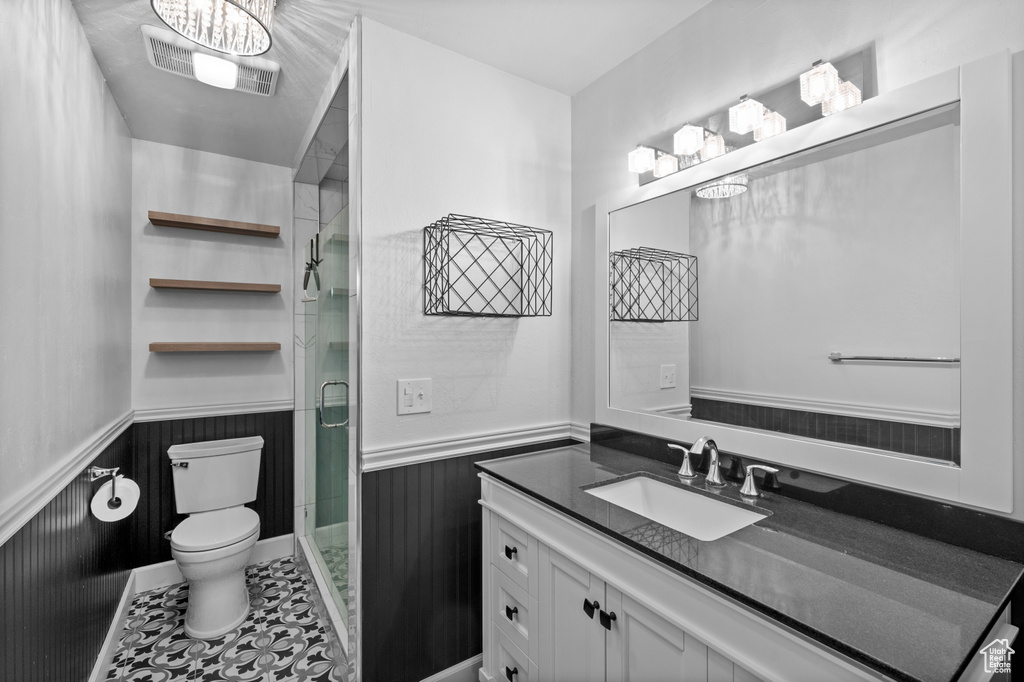 Bathroom with toilet, wainscoting, a shower stall, a chandelier, and vanity