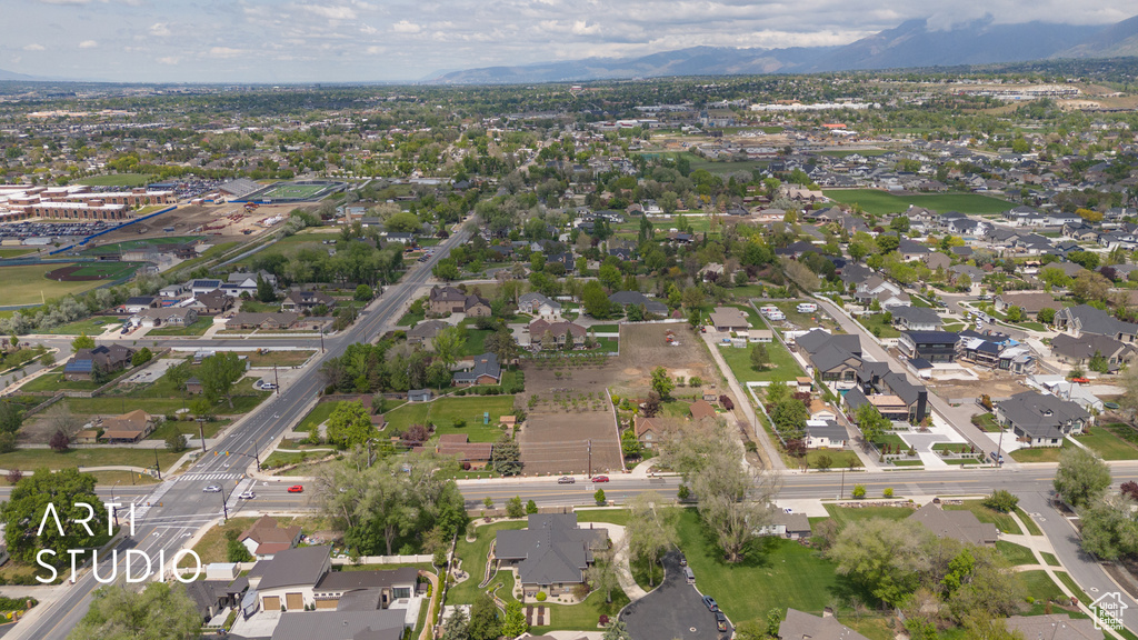 Aerial view of property and surrounding area featuring nearby suburban area and a mountain backdrop