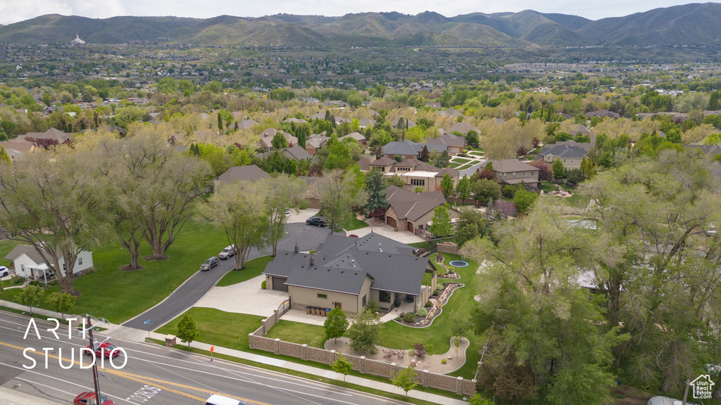 Aerial view of property and surrounding area featuring a mountain backdrop and nearby suburban area