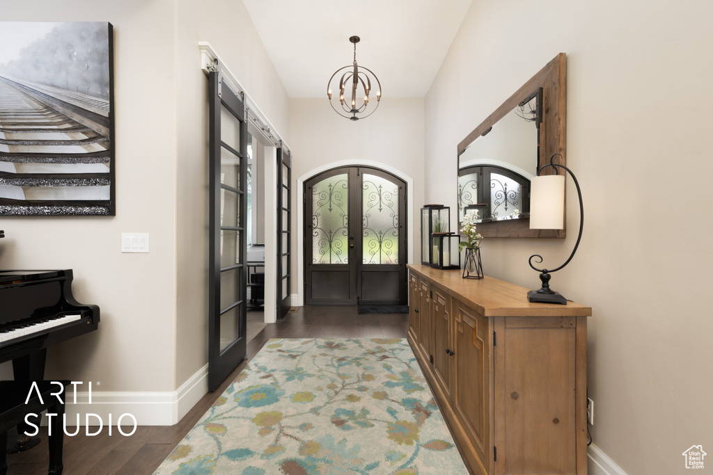 Foyer with french doors, baseboards, a chandelier, wood finished floors, and plenty of natural light