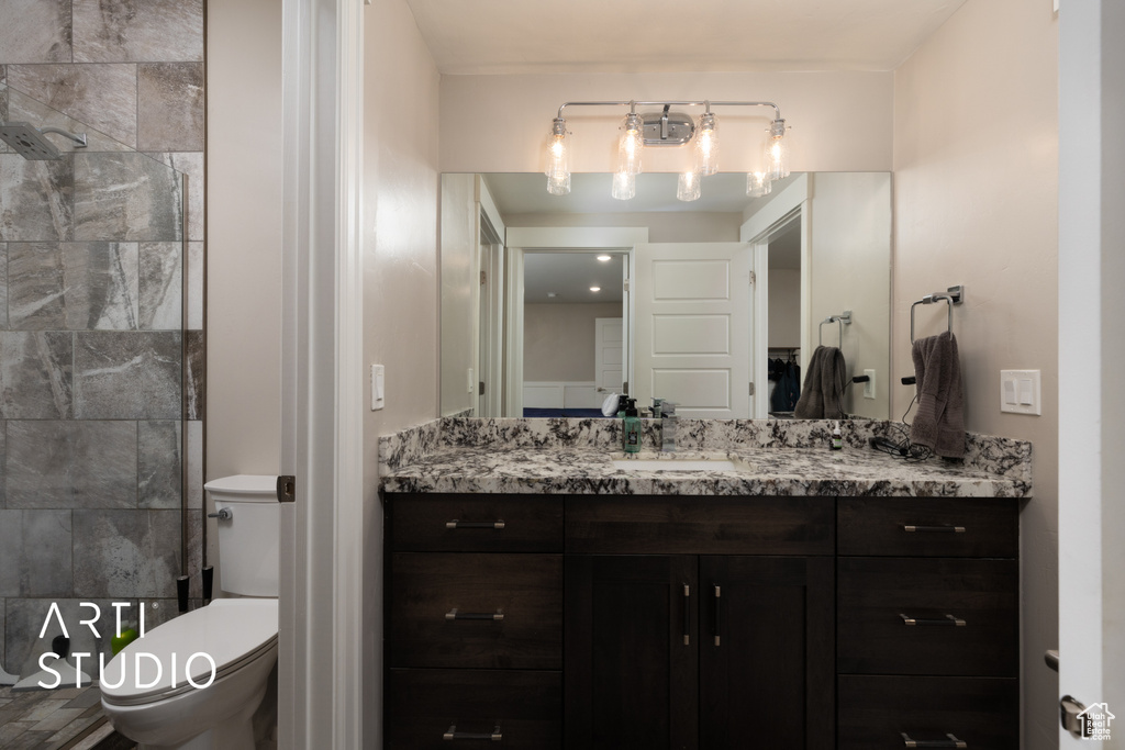 Bathroom with toilet, vanity, and a tile shower