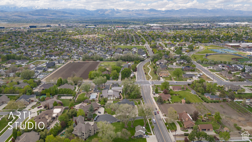 Aerial view of property and surrounding area featuring mountains and nearby suburban area