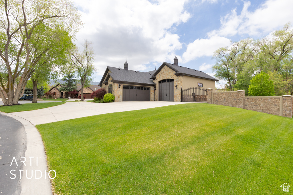 View of front facade with stone siding, a gate, concrete driveway, and an attached garage