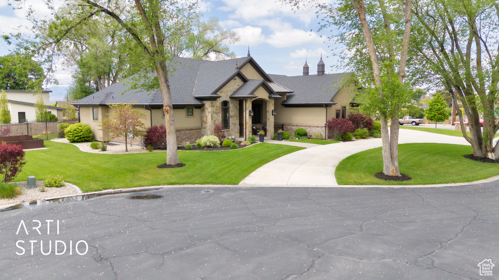View of front facade featuring stone siding, a front lawn, and curved driveway
