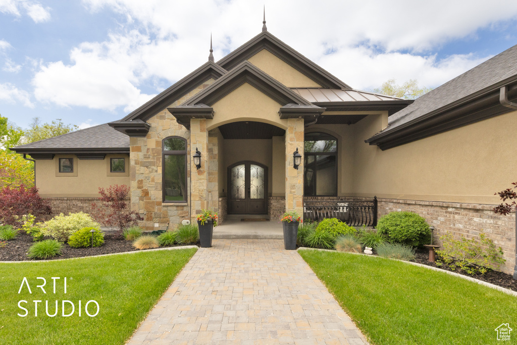 View of front of property with stucco siding, french doors, and a front yard
