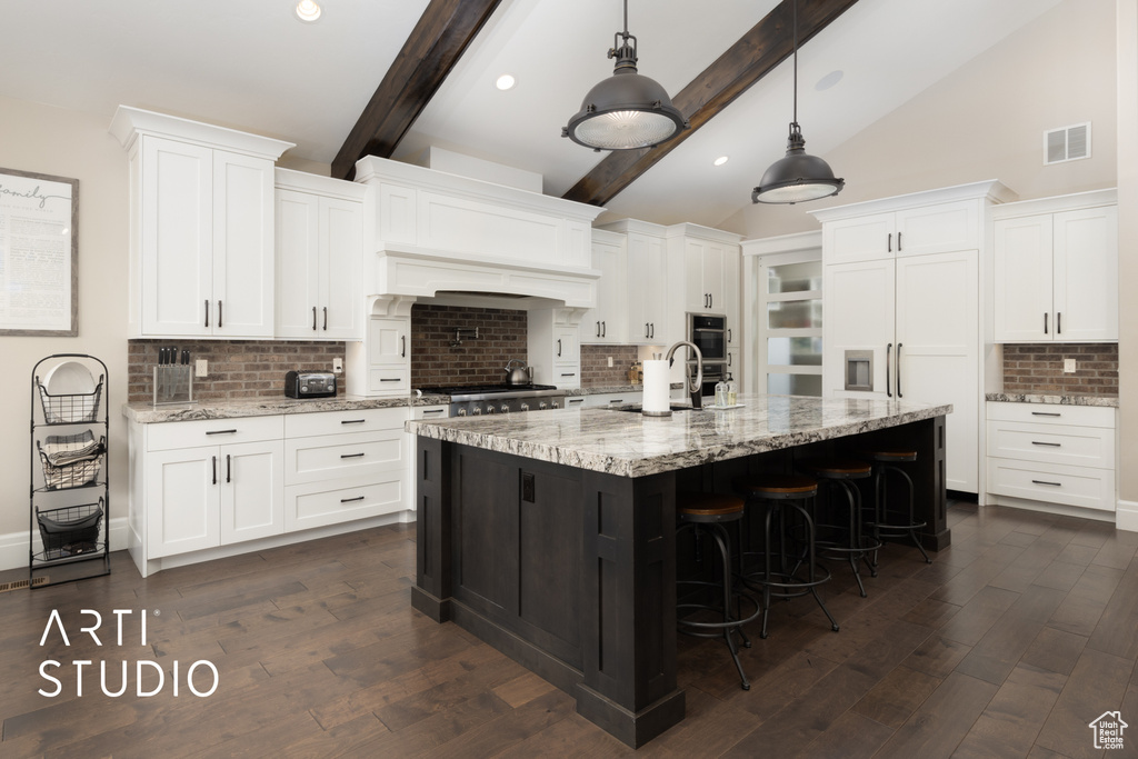 Kitchen with decorative backsplash, a breakfast bar area, white cabinetry, a sink, and recessed lighting