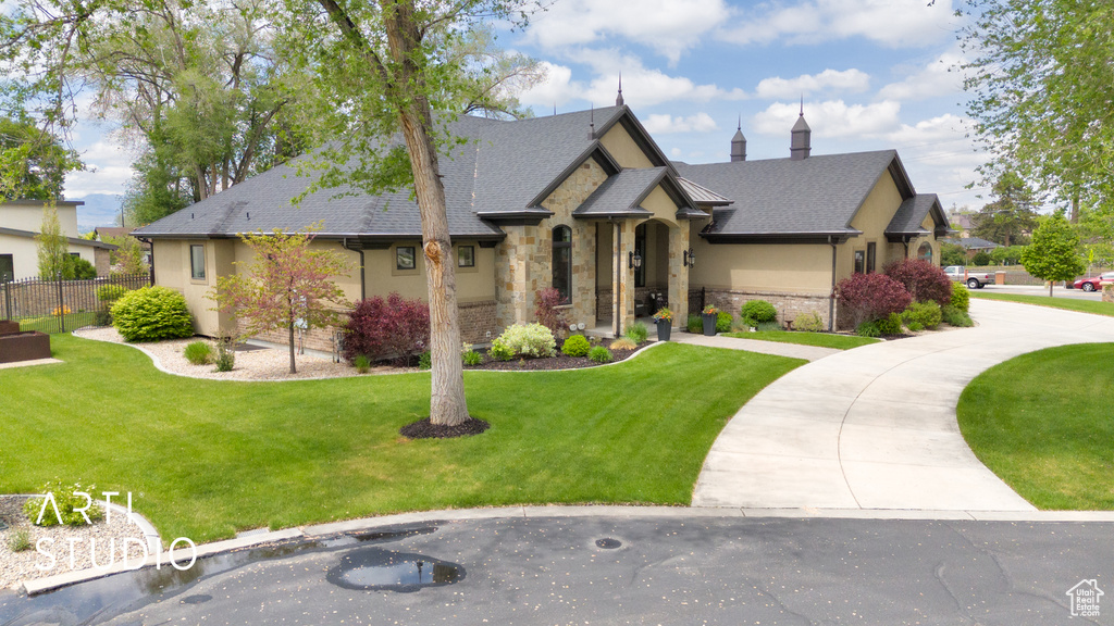 View of front of house with stone siding, stucco siding, and roof with shingles