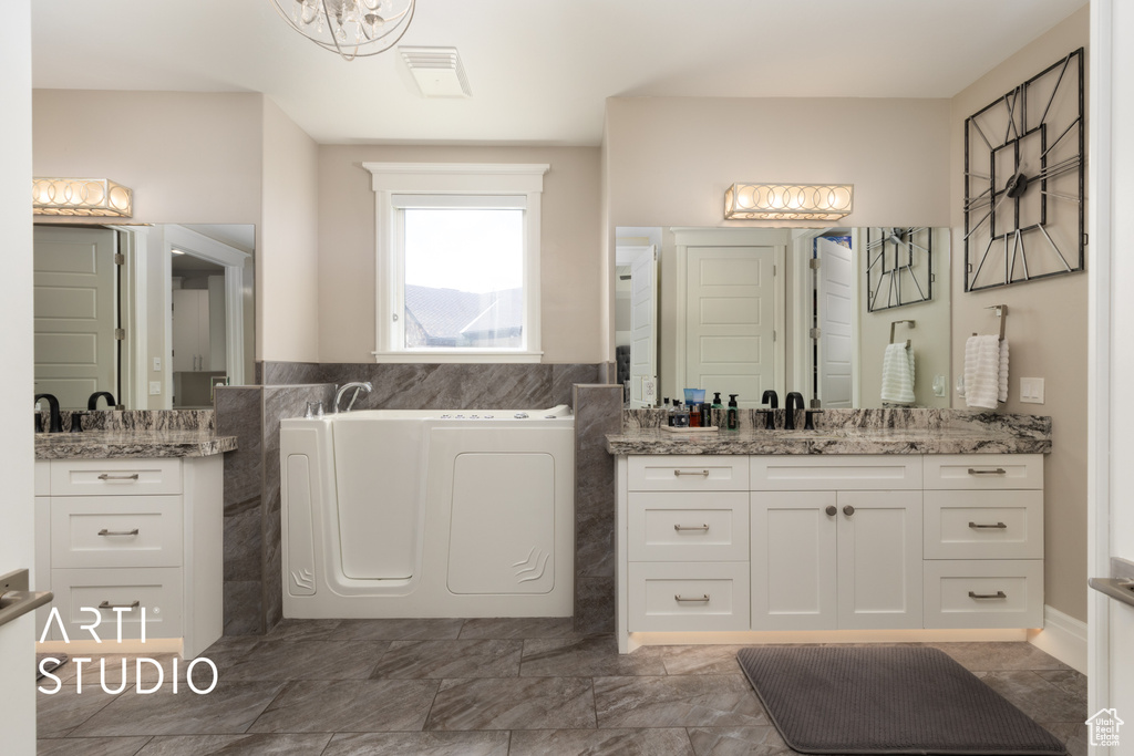 Bathroom with a bath, two vanities, and tile walls