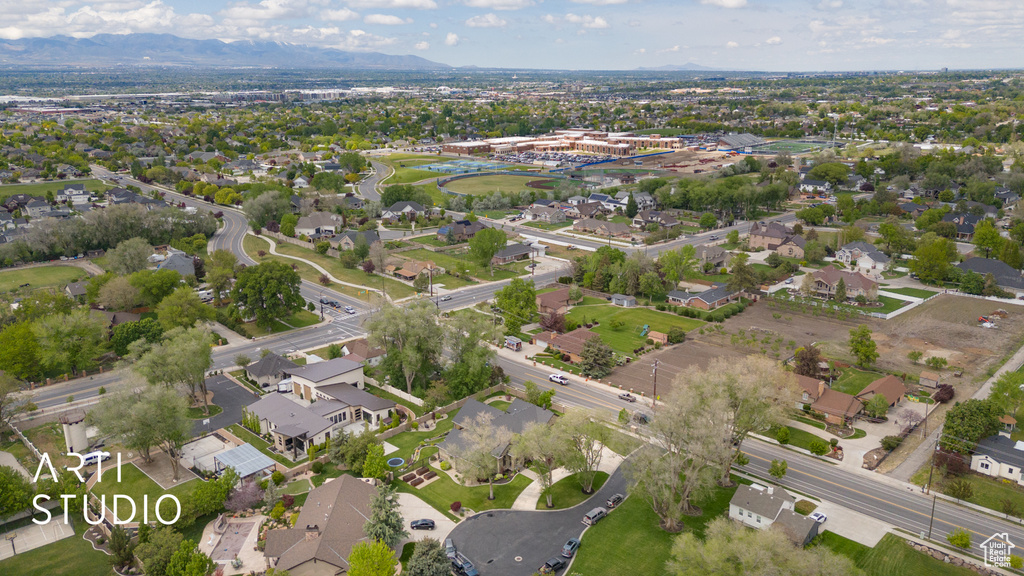 Aerial view of property and surrounding area featuring nearby suburban area and a mountain backdrop