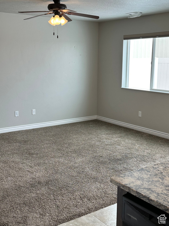 Unfurnished room with a textured ceiling, ceiling fan, carpet, and baseboards