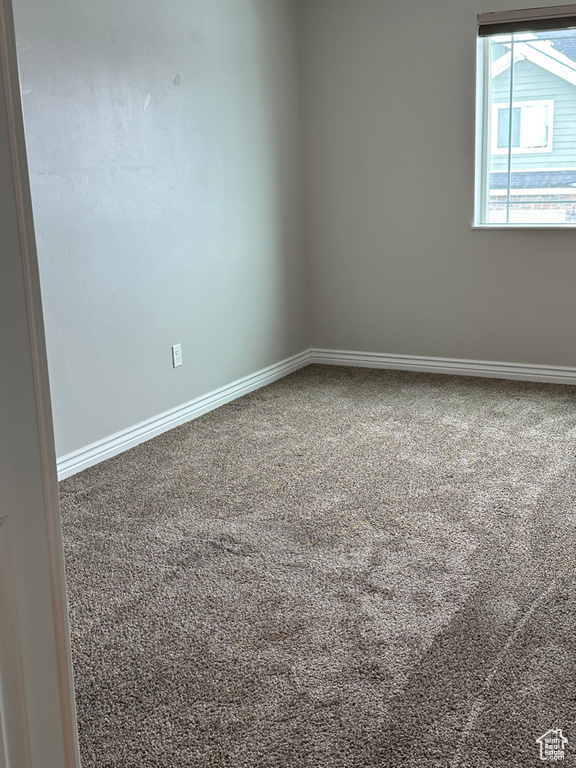 Carpeted empty room featuring baseboards