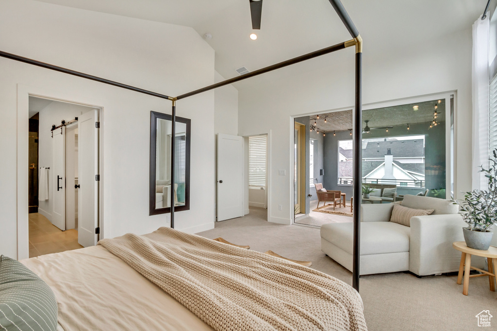 Bedroom with a barn door, access to exterior, light colored carpet, high vaulted ceiling, and baseboards