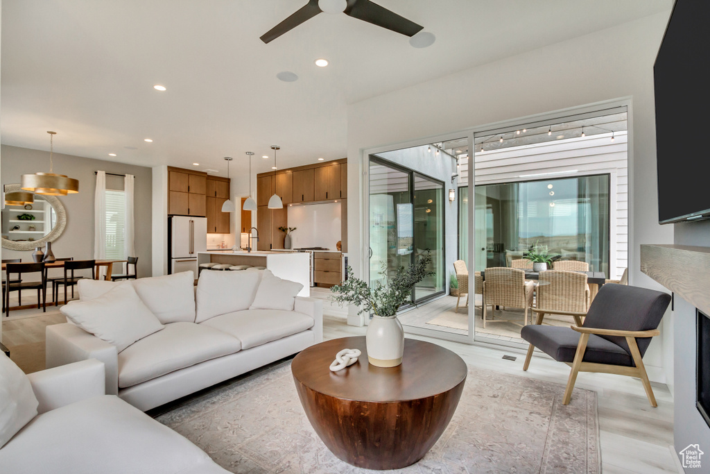 Living room featuring healthy amount of natural light, ceiling fan, light wood finished floors, and recessed lighting