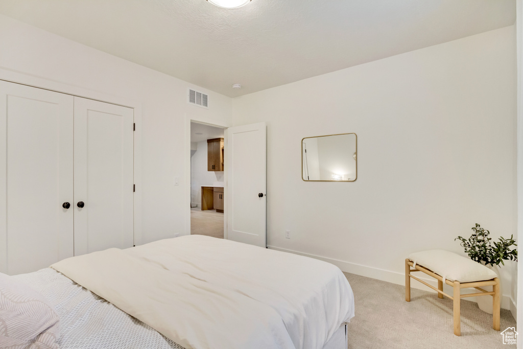 Bedroom featuring light colored carpet, a closet, and baseboards