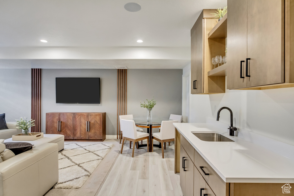 Kitchen featuring a sink, open floor plan, light wood-style floors, light countertops, and recessed lighting