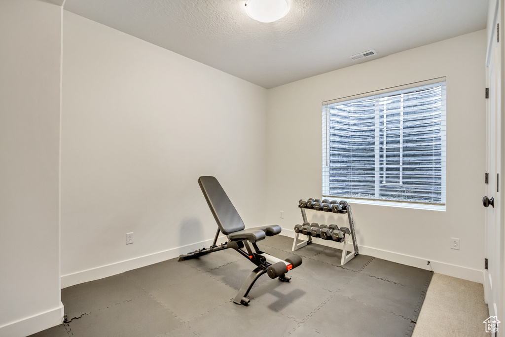 Workout area featuring baseboards and a textured ceiling