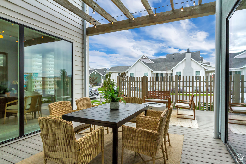 View of wooden balcony featuring a deck, outdoor dining space, and a residential view