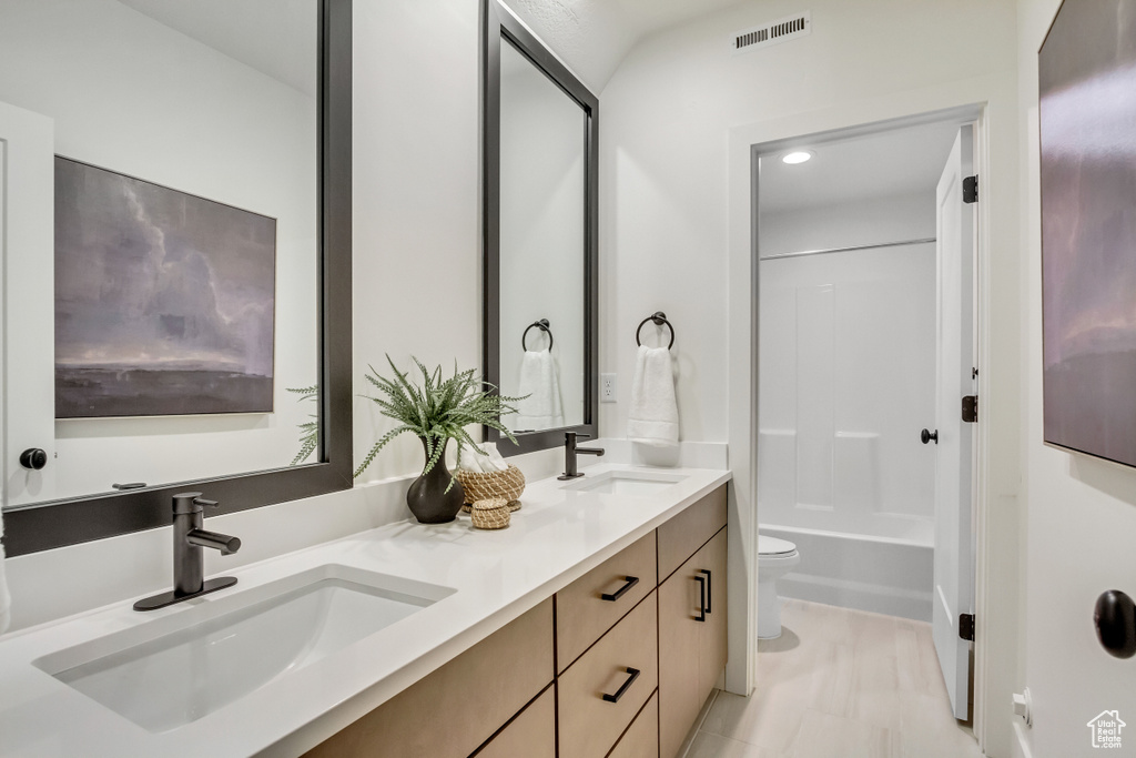 Bathroom with toilet, double vanity, and bathtub / shower combination