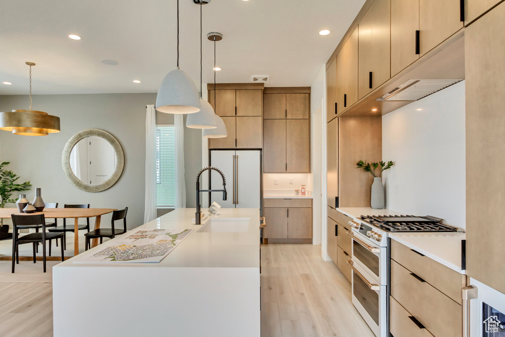 Kitchen featuring white appliances, a sink, light wood-style floors, recessed lighting, and light countertops