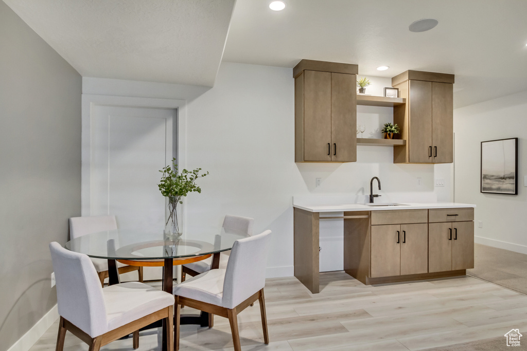Kitchen with open shelves, a sink, baseboards, light wood finished floors, and light countertops
