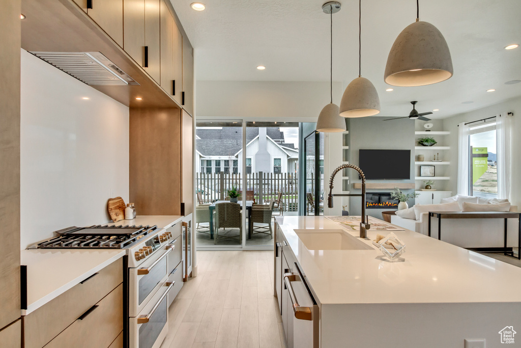 Kitchen featuring range with two ovens, a sink, a ceiling fan, light wood-type flooring, and light countertops