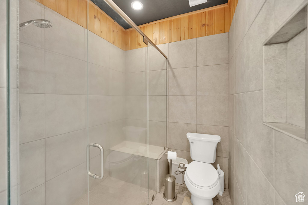 Full bath featuring toilet, a shower stall, tile walls, and recessed lighting