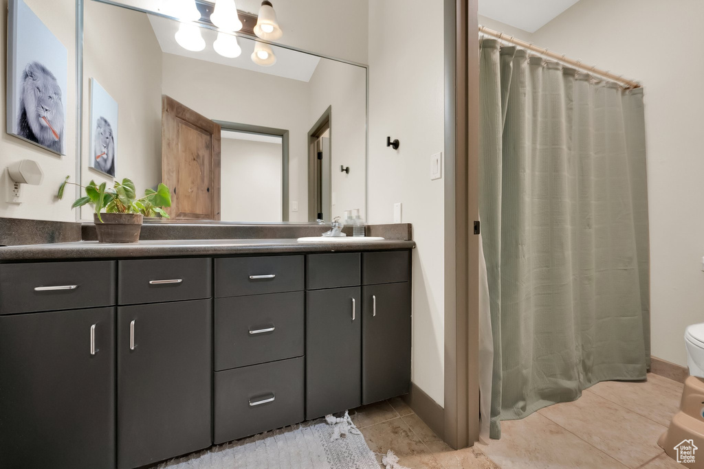 Full bathroom with double vanity, toilet, tile patterned flooring, and curtained shower