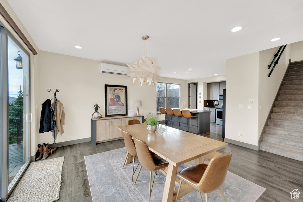Dining area with stairs, an AC wall unit, wood finished floors, recessed lighting, and baseboards