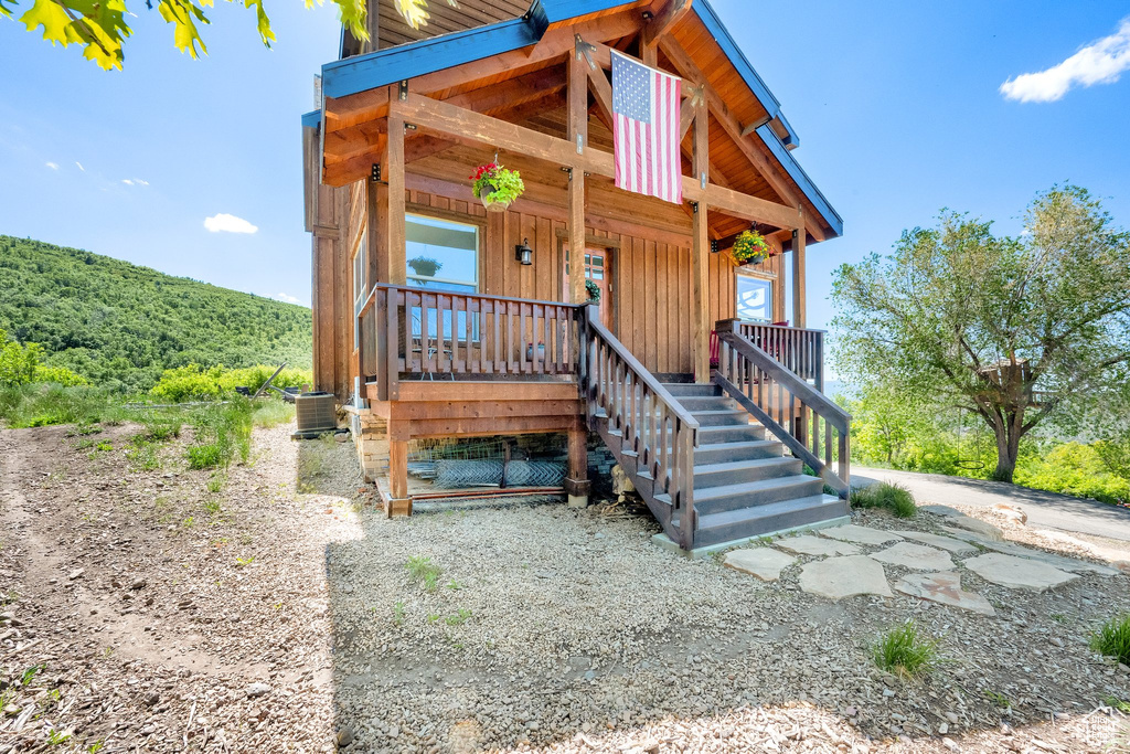 View of front facade featuring central AC, a porch, board and batten siding, and stairway
