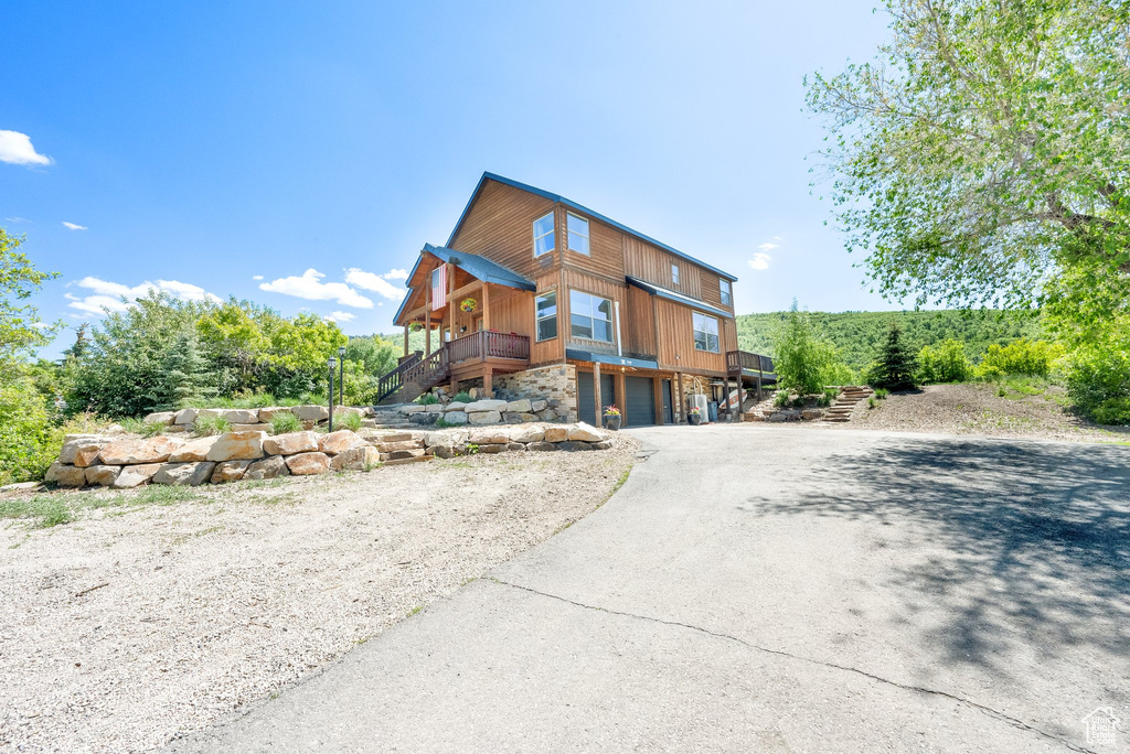 Chalet / cabin with asphalt driveway, stairs, and an attached garage