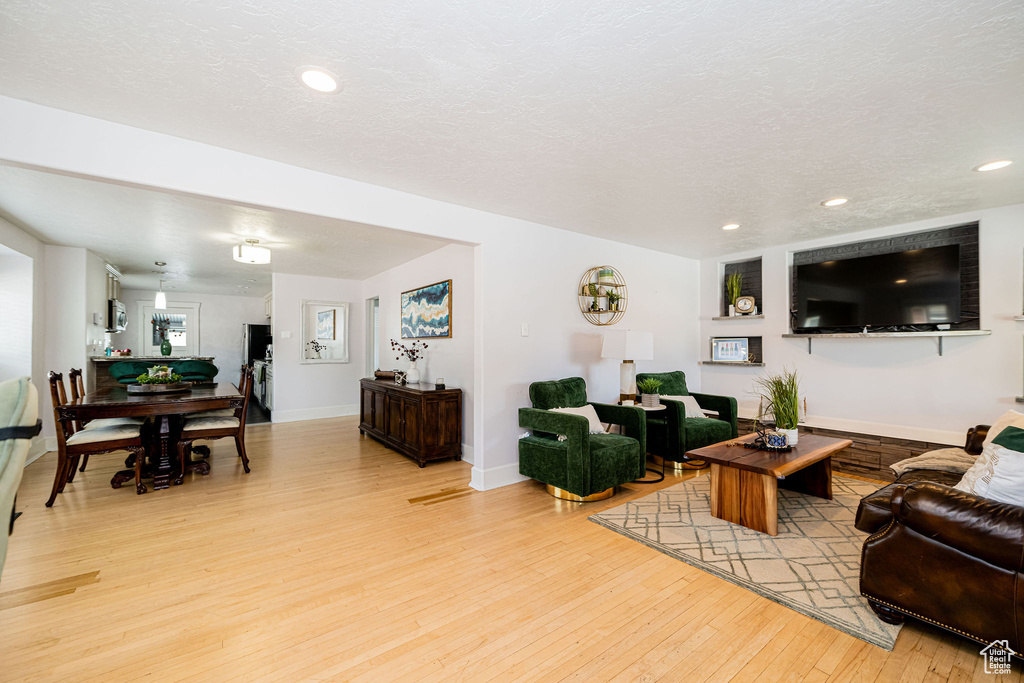 Living area featuring light wood finished floors, recessed lighting, baseboards, and a textured ceiling