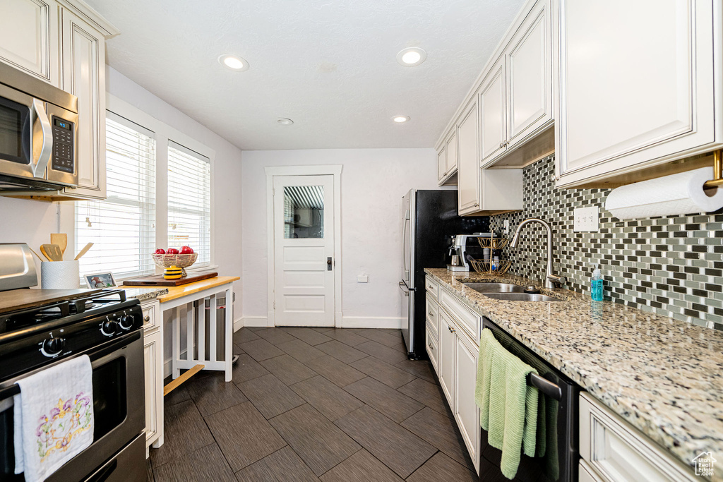 Kitchen featuring a sink, appliances with stainless steel finishes, tasteful backsplash, recessed lighting, and baseboards
