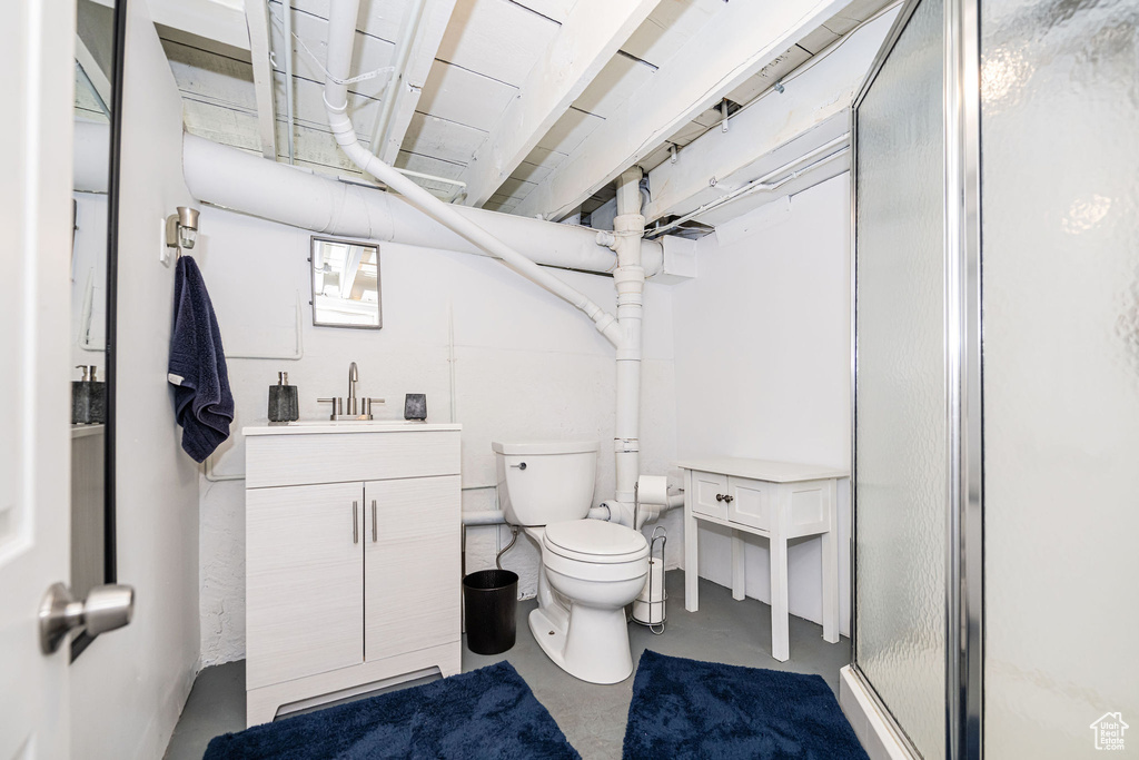 Full bathroom with finished concrete flooring, a shower stall, toilet, and vanity