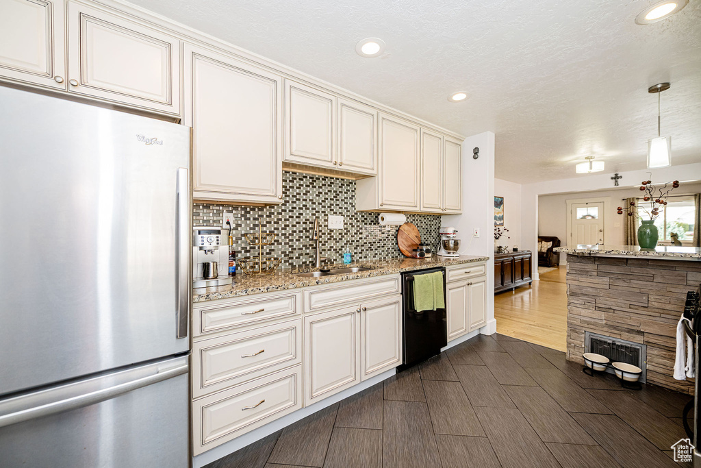 Kitchen with freestanding refrigerator, dishwasher, tasteful backsplash, recessed lighting, and light stone countertops