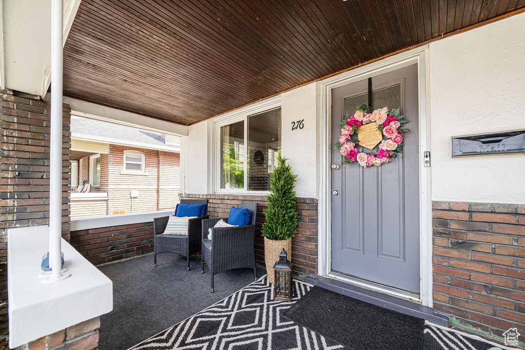 Property entrance featuring covered porch and brick siding