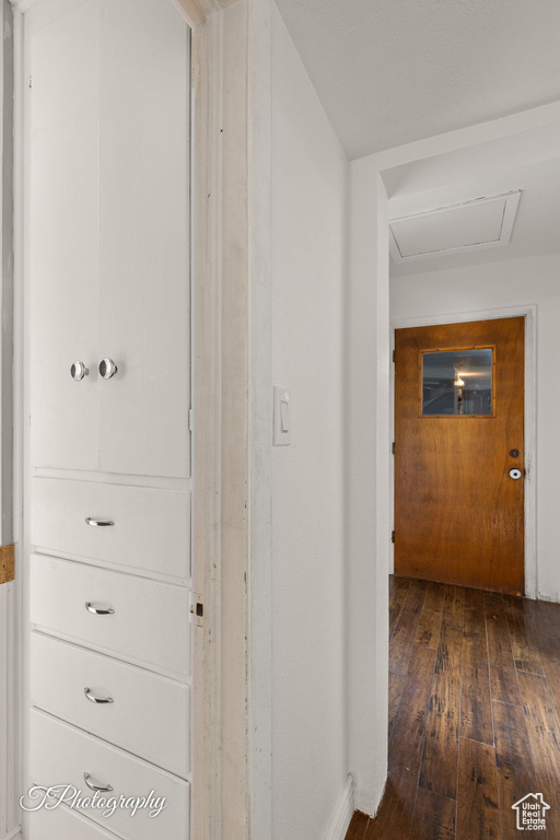 Hallway featuring hardwood / wood-style flooring, attic access, and baseboards