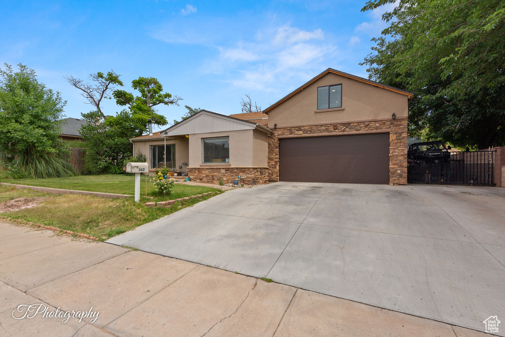 View of front of home with stucco siding, stone siding, and concrete driveway