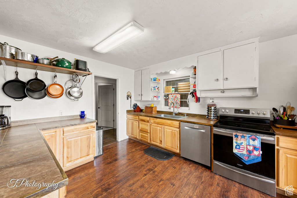 Kitchen with appliances with stainless steel finishes, open shelves, a sink, and dark wood finished floors