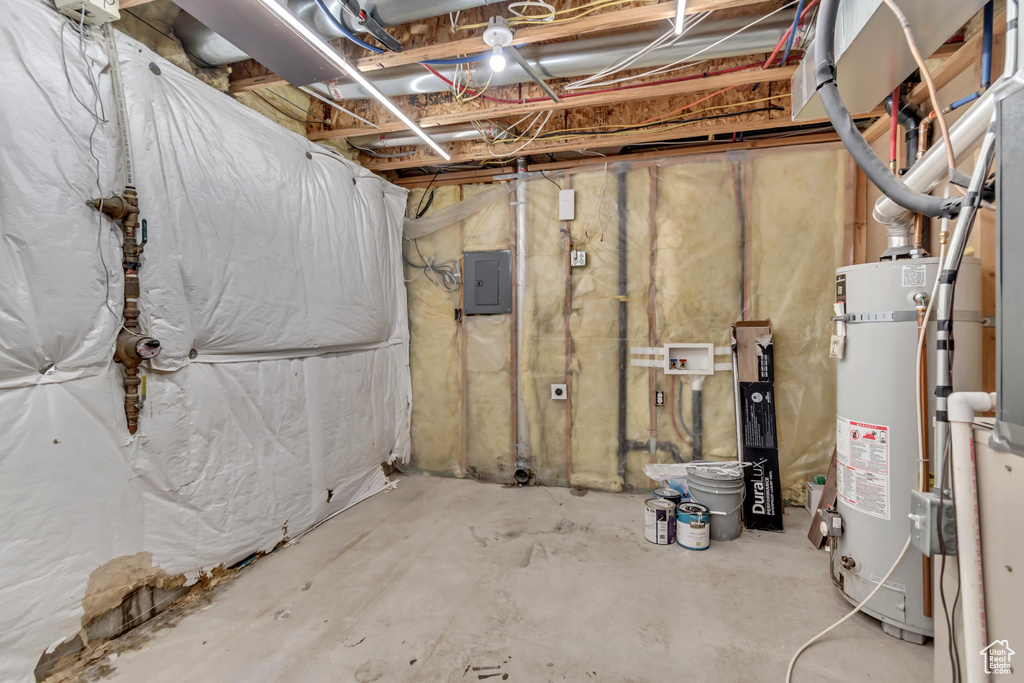 Unfinished below grade area with gas water heater and electric panel