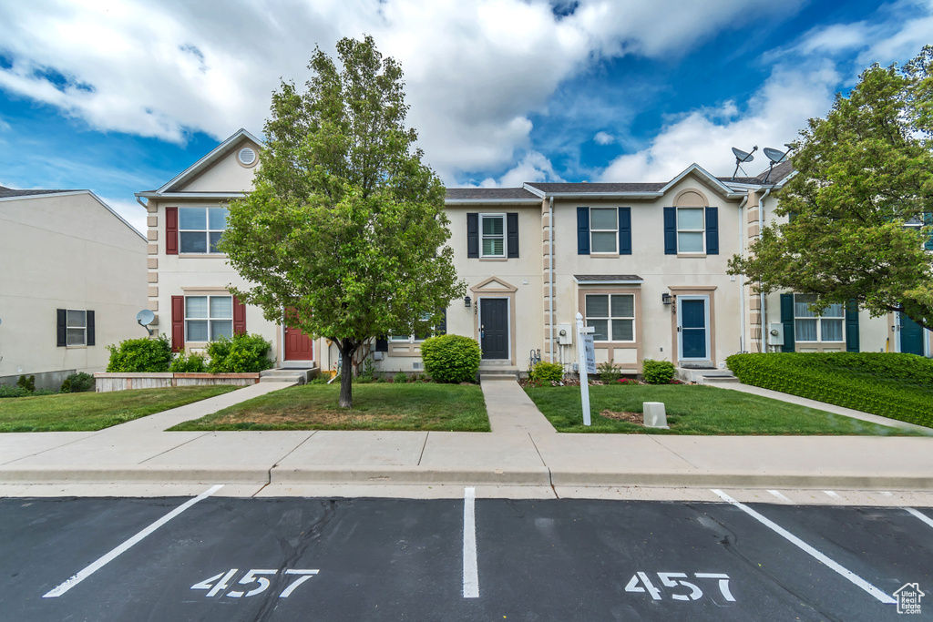 Multi unit property with uncovered parking, a front yard, stucco siding, and entry steps