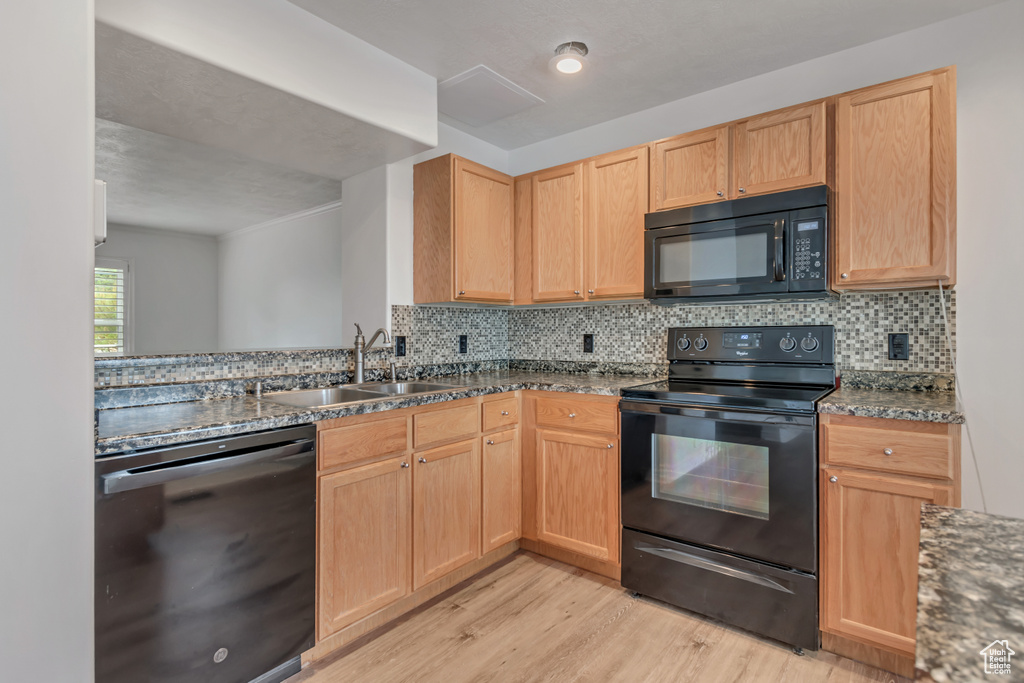 Kitchen featuring black appliances, a sink, light wood-style floors, and light brown cabinetry