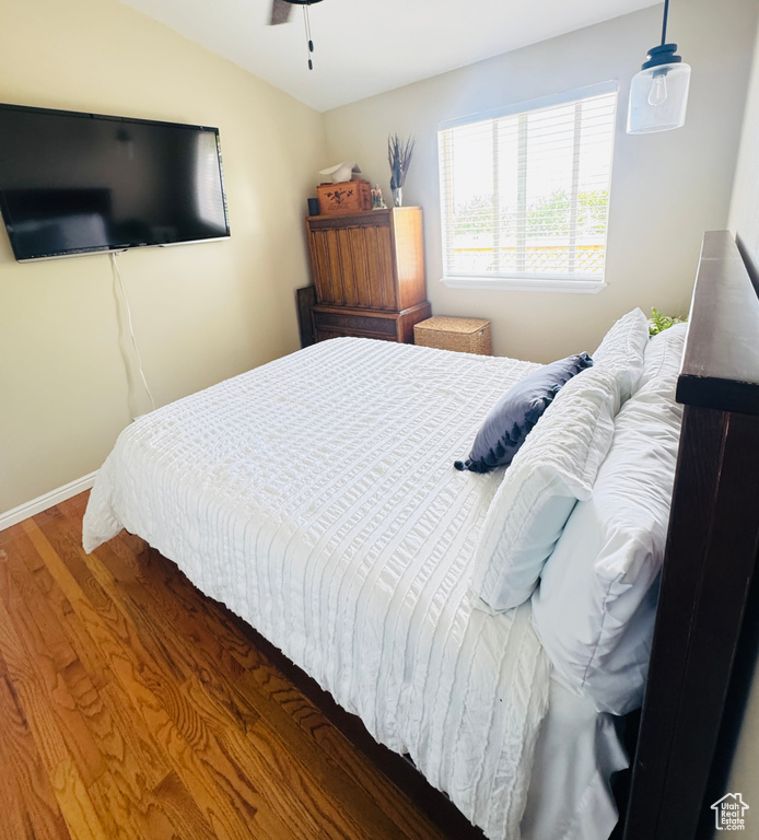 Bedroom featuring vaulted ceiling, wood finished floors, and baseboards