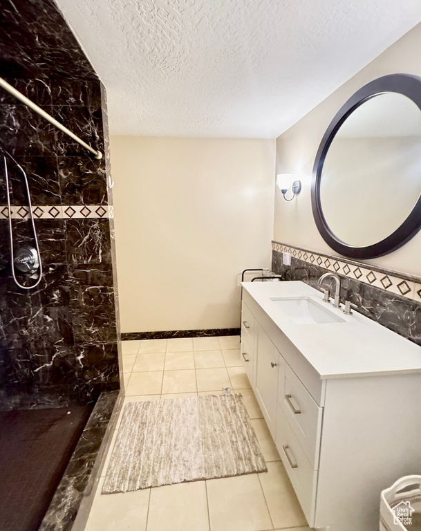 Full bath with walk in shower, a textured ceiling, tile patterned flooring, and vanity
