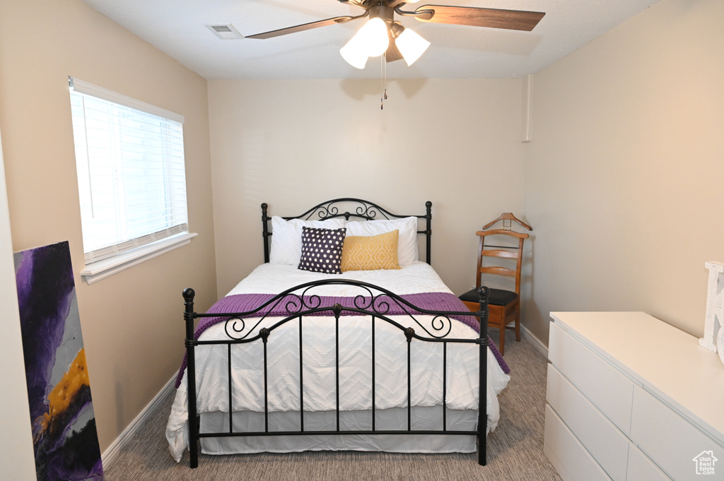 Carpeted bedroom with ceiling fan, baseboards, and visible vents