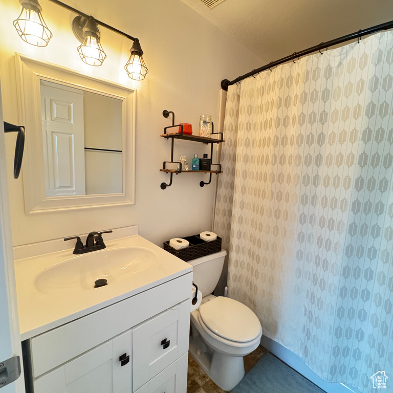 Full bath featuring vanity, toilet, a shower with shower curtain, and visible vents
