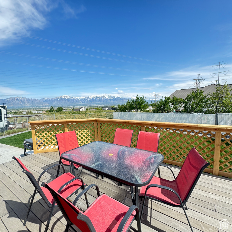 Wooden deck with outdoor dining area, a mountain view, and fence