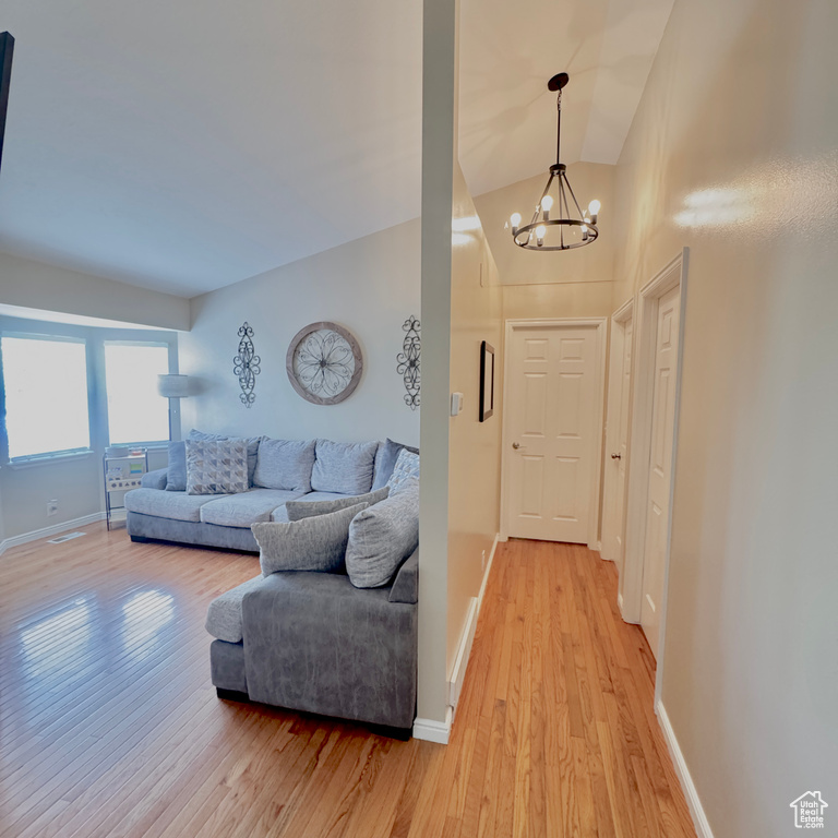 Living room featuring baseboards, a chandelier, and light wood-type flooring