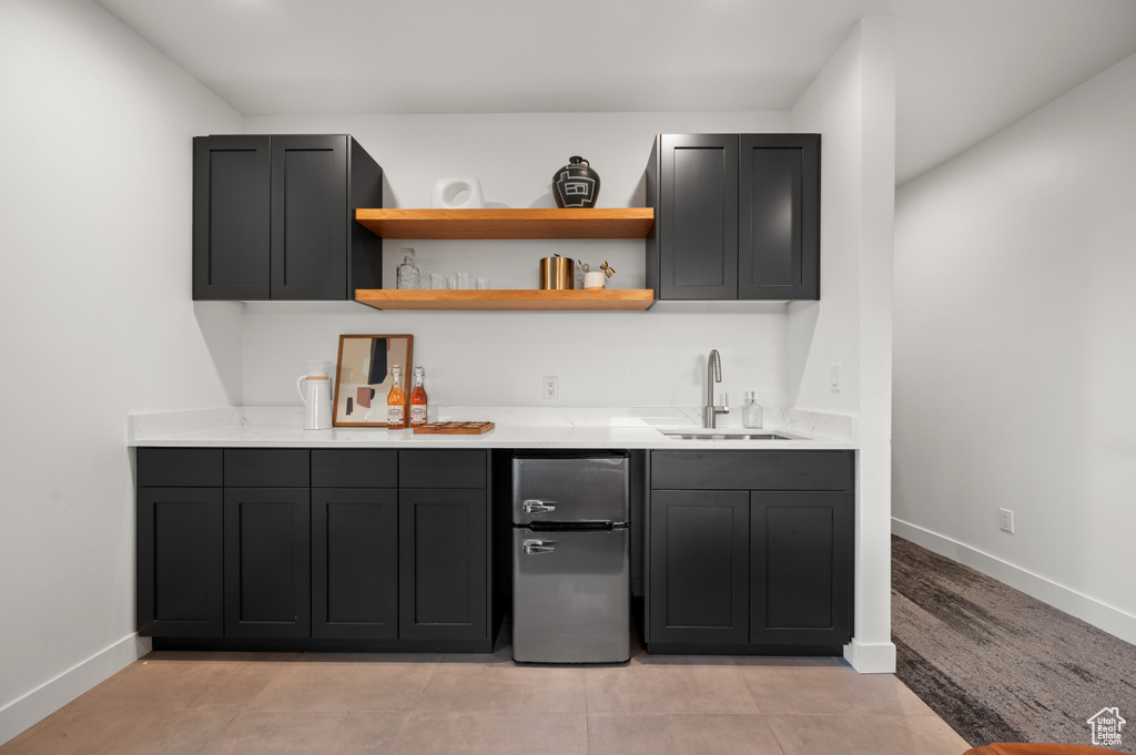 Bar featuring a sink, wet bar, freestanding refrigerator, and baseboards