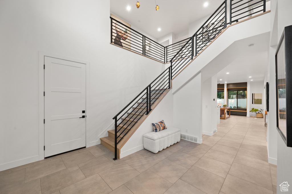 Entrance foyer featuring stairway, light tile patterned floors, and a high ceiling