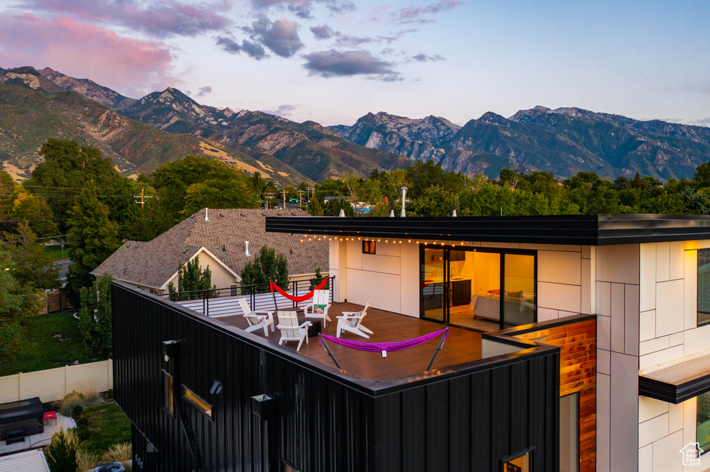 Back of property at dusk with fence and a mountain view